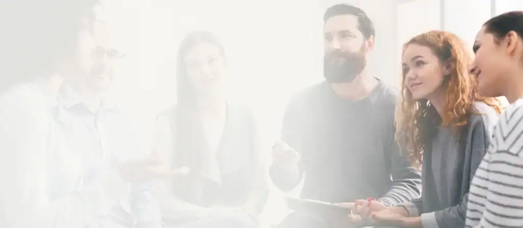 Five coworkers in a bright office discussing a project, one holding a tablet and gesturing.