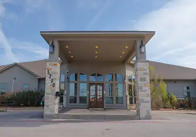 Front entrance of a low building with a covered portico, stone columns, and glass double doors; address 5200 visible on the left.