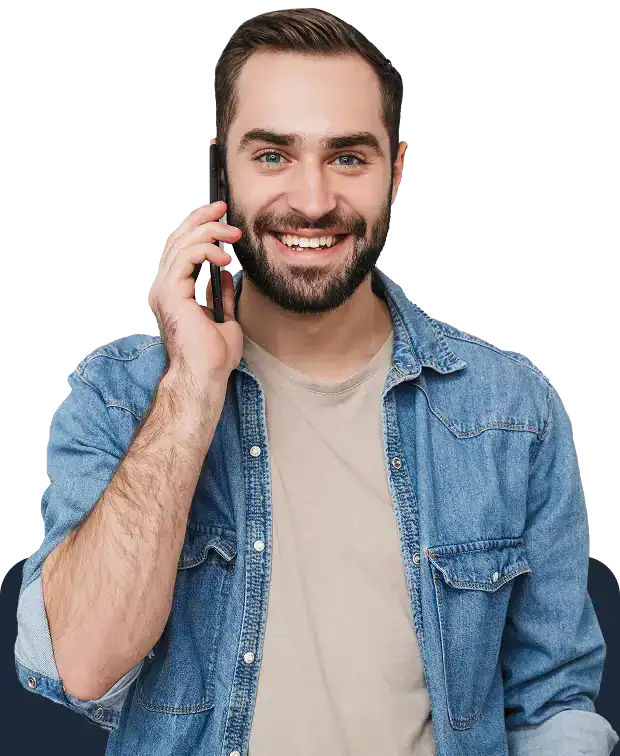 Smiling man with a beard wearing a denim shirt, talking on a cell phone